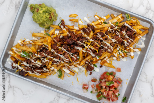 Overhead view of Latino food for a hungry patron includes a huge plate of asade fries loaded with cheese and sour cream