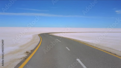 Winding Road Through Vast Empty Salt Flat Under Clear Blue Sky