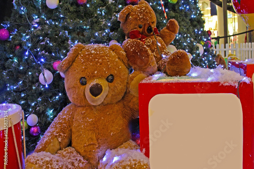 Toys teddy bear dolls under shiny Christmas tree during festive period