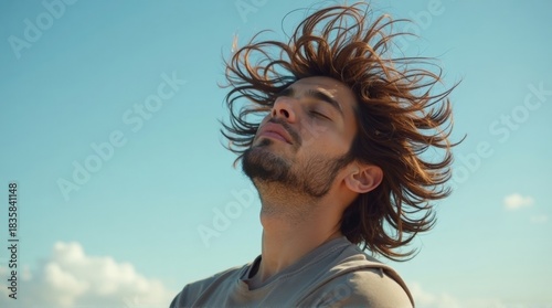 Relaxed Young Man with Long Hair Windswept Outdoors Under Blue Sky