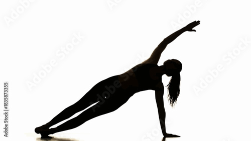 Silhouette of a woman performing a side plank exercise.