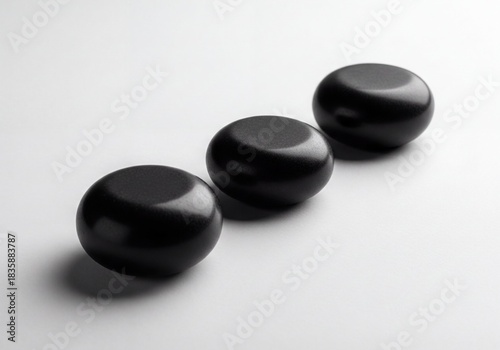 Three Smooth Black Round Objects in Minimalist Diagonal Arrangement on White Background