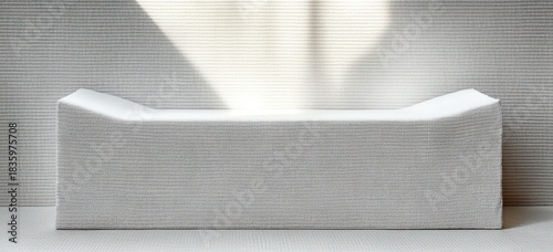 Minimalist white textured bench or seating element in a modern room with soft natural light casting shadows on ribbed wall and floor surfaces