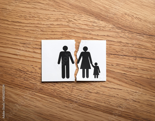 Separated family paper figures on wooden background depicting divorce