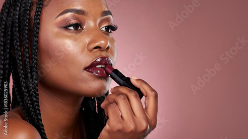 Black woman applying dark glossy lipstick