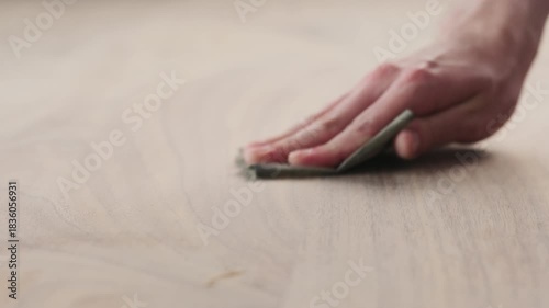 Slow motion slide orbit shot of man hand sanding black walnut wood table
