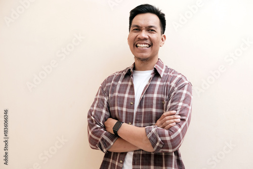 Southeast Asian man wearing flannel shirt standing and smiling expression happy with arm crossed, on white isolated background