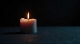 A single burning candle casts a warm, gentle glow in the profound darkness, illuminating a moment of quiet reflection or solemn remembrance