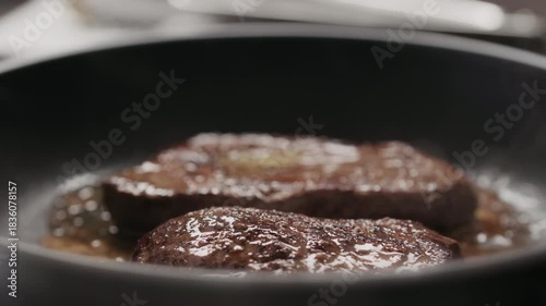 Slow motion two beef steak pieces frying on nonstick pan