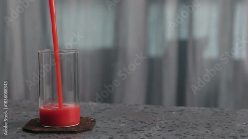 Slow motion pour tomato juice into glass on concrete surface with copy space