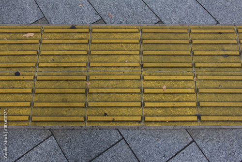 Wallpaper Mural Yellow blocks of tactile paving for blind handicap. Tactile pavement for the visually impaired close up background. Texture of gray  square paving tile with Braille blocks in autumn. Torontodigital.ca