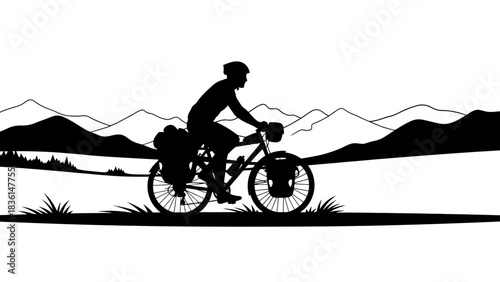 Silhouette of a touring cyclist riding a bicycle through a scenic mountain landscape.