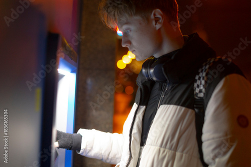 фотографія Young man interacts with electronic ticketing device, Casual young man utilizes