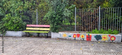 Colorful painted flowers on concrete wall in urban park with wooden bench – outdoor public space