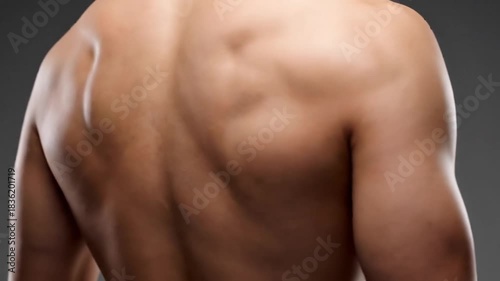 Close up Profile View of a Muscular Male Torso Showing Chest and Shoulder Muscles with Subtle Lighting on a Gray Studio Background