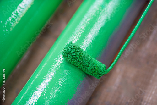 Roller Brush Painting, Man worker painting green color on steel surface pipe line by the roller brush for protection and corrosion.