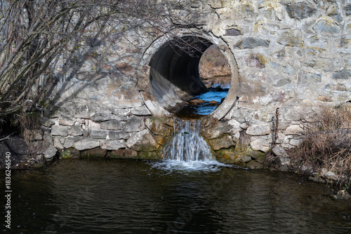 Sewage water flowing through a concrete pipe in to a small pond polluting the environment.