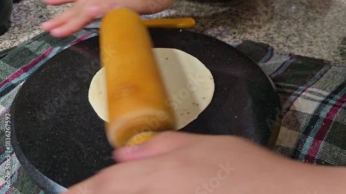 macro shot showing indian snack samosa being rolled with a rolling pin on a marble top shows puri roti bread also being made, popular Indian street food