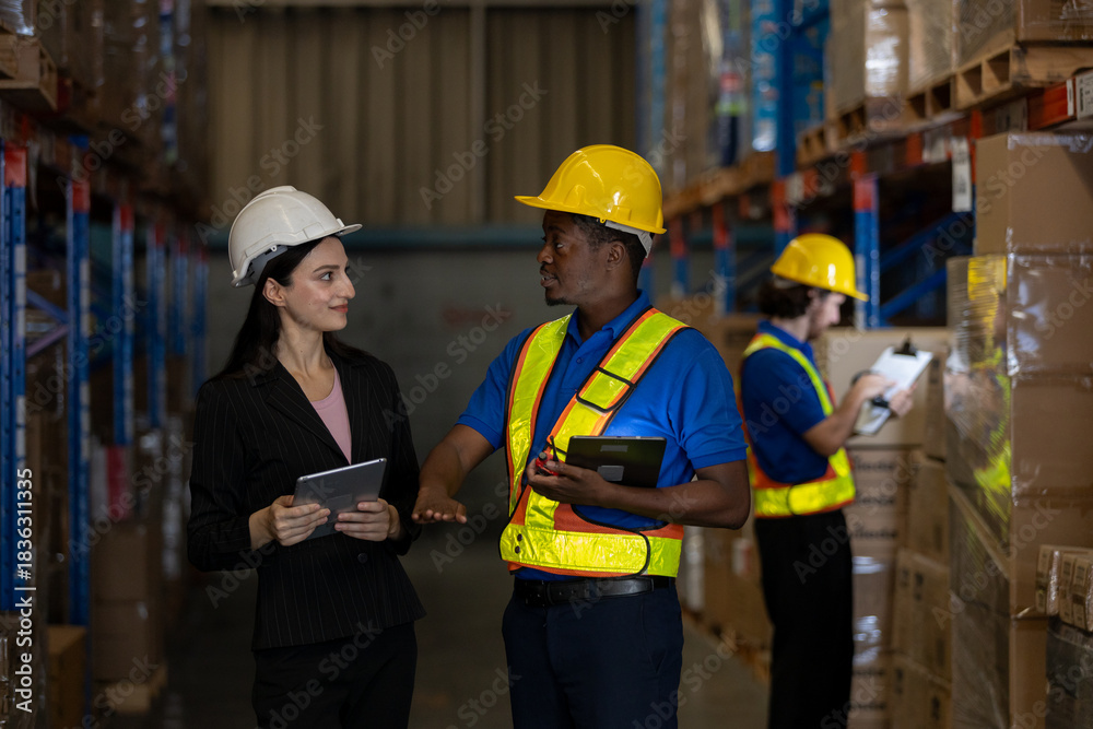 Obraz premium Warehouse worker and female supervisor discussing logistics tasks with digital tablets while another staff inspects inventory. Concept of teamwork, digital operations and smart supply chain