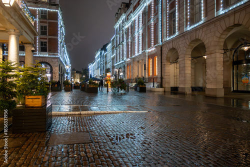 Walking on streets of Central London in Covent Garden decorated with Christmas lighting and green Christmas trees with garlands, December holidays in England