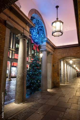 Walking on streets of Central London in Covent Garden decorated with Christmas lighting and green Christmas trees with garlands, December holidays in England