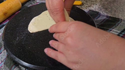 Preparation of Indian snack of samosa by cutting triangles of flattened bread and then folding into a cone ready to be filled and fried
