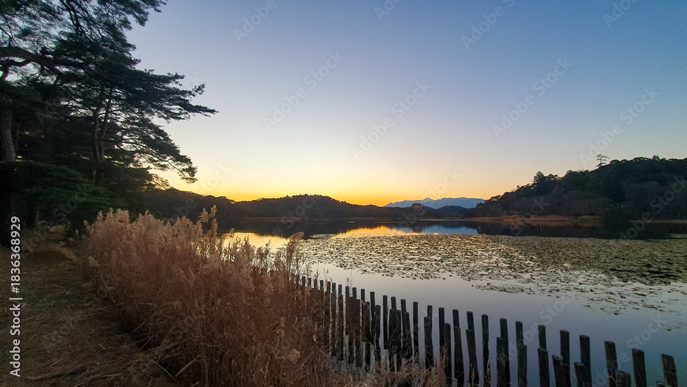 Obraz premium Scenic Lakeside Boardwalk at Sunset with Mountain Silhouette. 
