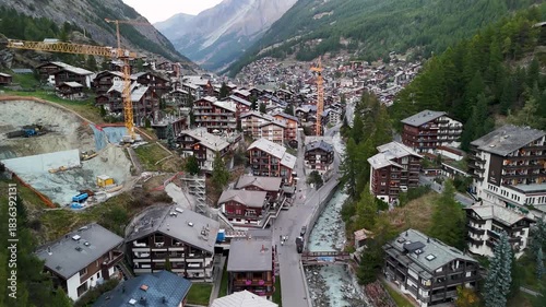 Aerial tracking shoot of Midday Zermatt with constructions crains visible city alpine village Switzerland
