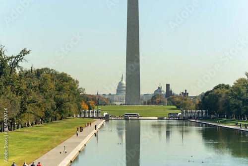 Valokuva People walk alongside the reflecting pool with the US Capitol and Washington Mon