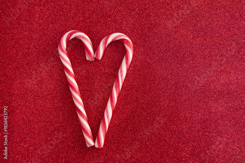 Christmas Candy canes as love heart on red background with copy space
