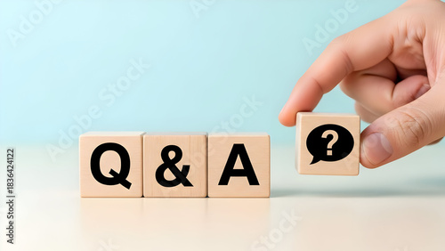 Q and a concept with wooden blocks and hand