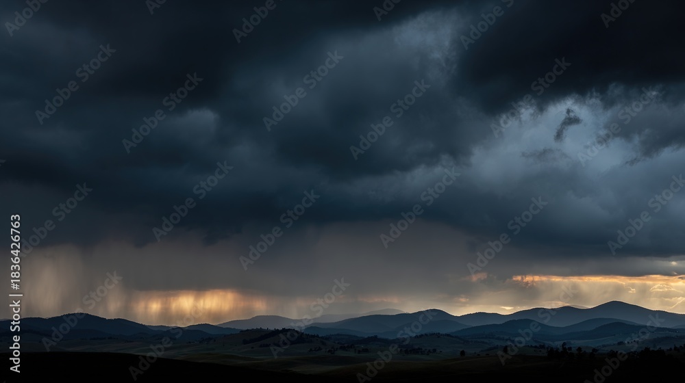 Obraz premium Storm clouds and distant rainfall over layered mountain landscape at dusk