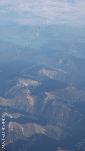 Alpine mountains visible from a plain that is flying over clouds