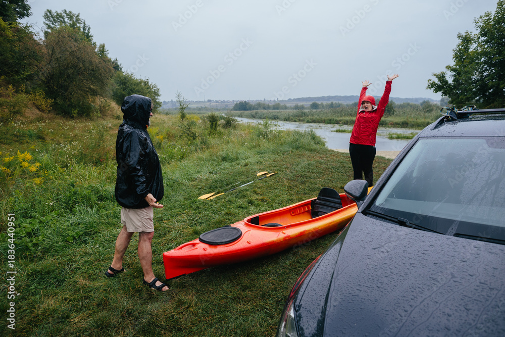 Fototapeta premium Senior couple enjoying outdoor kayaking in the rain