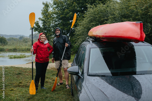 Senior couple enjoying rainy kayaking adventure with paddles