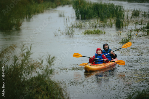 Senior couple actively kayaking together in the rain