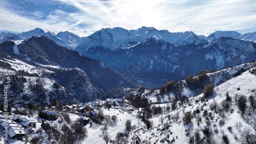 small village and large mountain ranges in winter in french alps