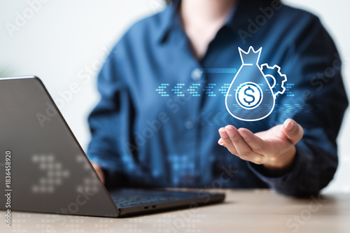 Obraz na plátně A hand presenting a digital money icon above a laptop, symbolizing budgeting, cashflow management, financial planning, and digital finance operations in a modern workspace