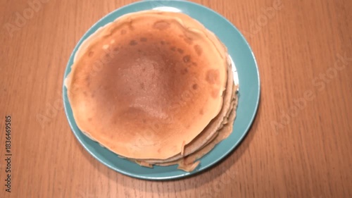 Stack of golden pancakes on a teal plate, ready to be enjoyed