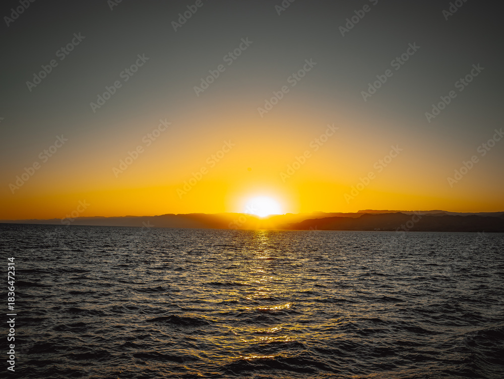 Naklejka premium Sunset over the Red Sea in Aqaba with golden sky and shimmering water