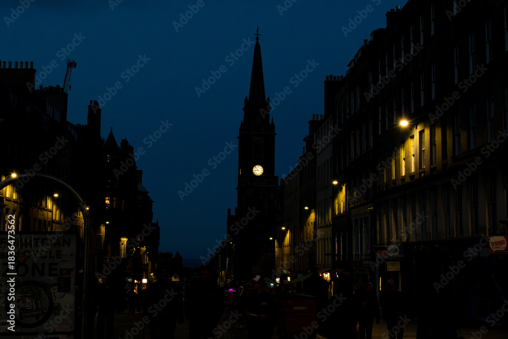 Fototapeta premium Night street scene on the Royal Mile in Edinburgh with illuminated clock tower