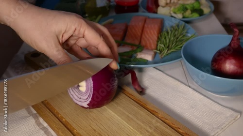 Chef slicing fresh red onion on wooden cutting board