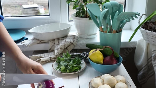 Woman's hands slicing red onion for a healthy fish dinner