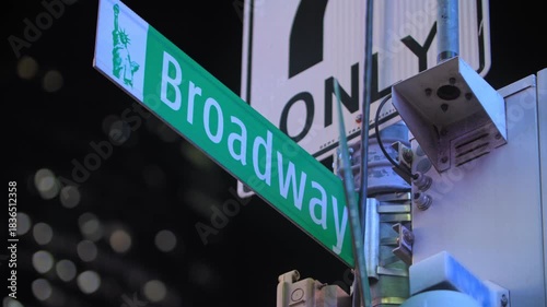 Close up hand held b-roll footage of Broadway street sign in Times Square New York at night with bright lights illuminating the iconic street corner