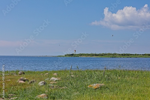 Coastal baltic landscape featuring a small day beacon or minor lighthouse situated on a low, scrubby Vahase saar island across a body of water in summer with clouds in the sky, Abruka,Saaremaa,Estonia