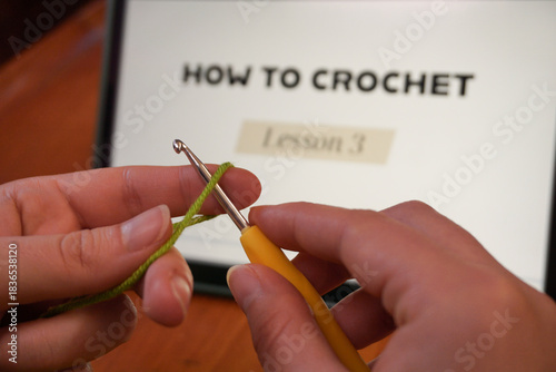Tablet with a crochet course open, yarn and female hands in frame; online DIY craft learning scene. Learning New Skills