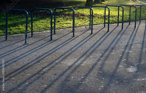 Im Boden verankerte Metallbügel werfen lange, symmetrische Schatten auf dem Gehweg