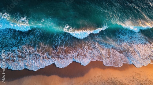 Waves roll onto a sandy beach creating a beautiful contrast with the deep blue sea. The scene captures the peacefulness and movement of nature at sunset.
