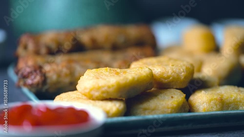 Crispy fried chicken wings, chicken nuggets and beef kebab in a plate. Kebab is Dipped into a Ketchup Bowl on a Table with Black Background a Macro Shot in 4K.