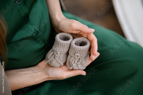 female hands in a white sweater with a knitted socks on a wooden background. close - up.